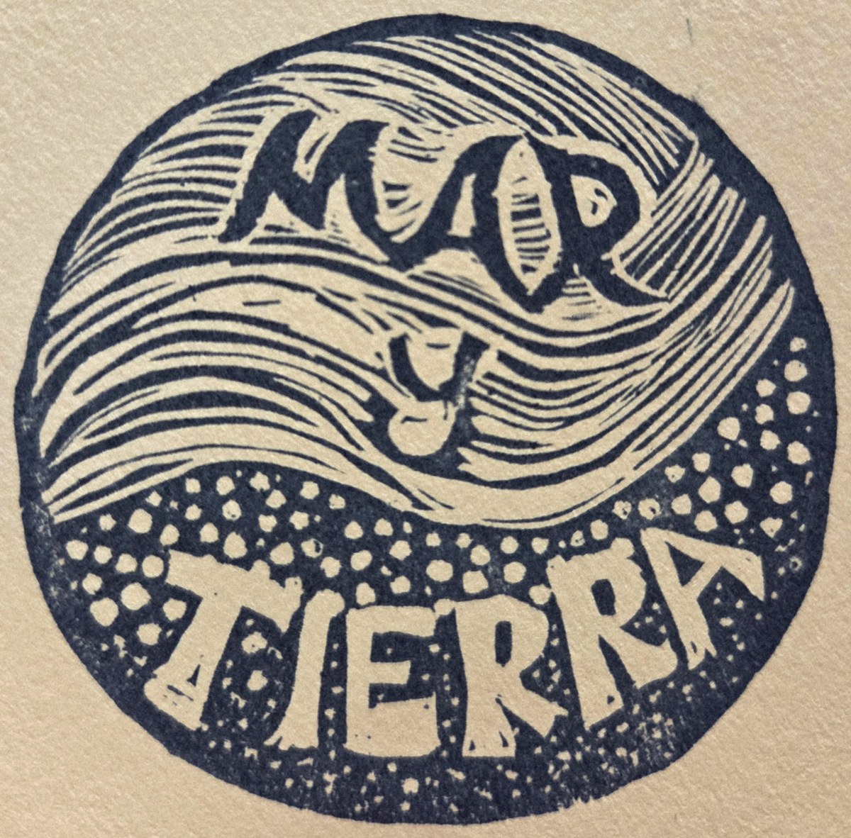 The Mar y Tierra seal: a hand-carved circle with a wave breaking over soil, printed in navy ink on kraft paper.