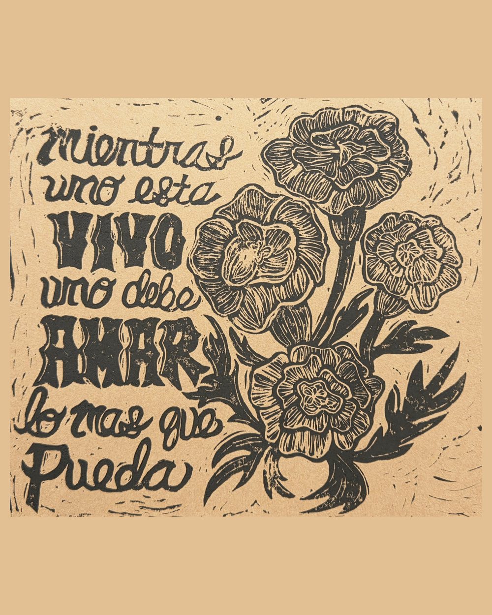 Linocut in black on kraft paper: four cempasúchil marigolds on leafy stems beside hand-lettered Spanish reading mientras uno está vivo uno debe amar lo más que pueda.